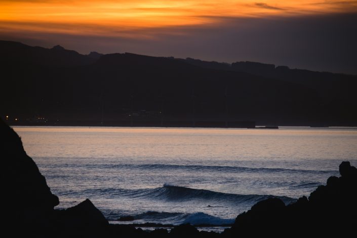 surfistas surfeando en Sopela al atardecer
